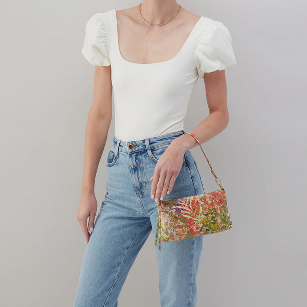 A Model Carrying a HOBO Darcy in Tropic Floral Printed Leather as a baguette bag with the single solid leather strap.