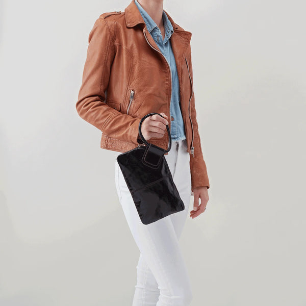 A Model holding onto the Circular Handle of the HOBO Sable Wristlet Crafted in Black Polished Leather.